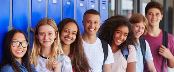 Teenage school kids smiling to camera in school corridor