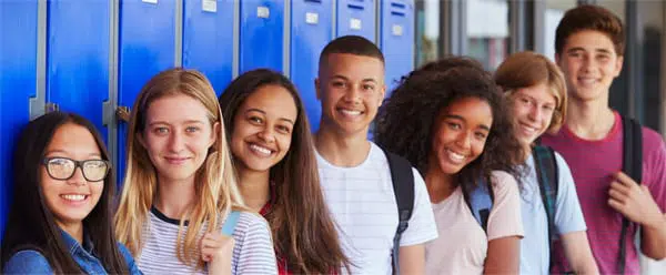 Teenage school kids smiling to camera in school corridor