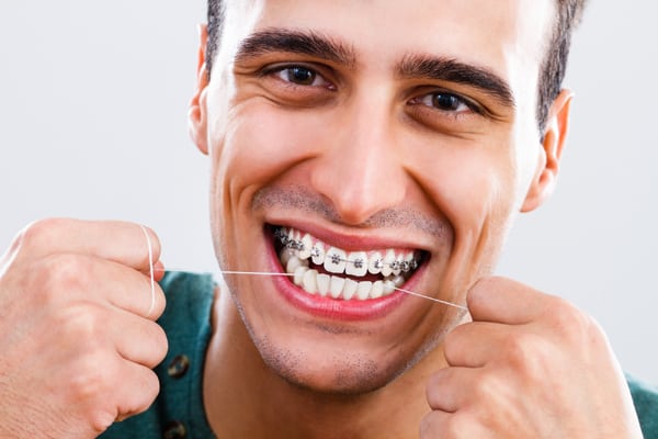 man-flossing-with-braces